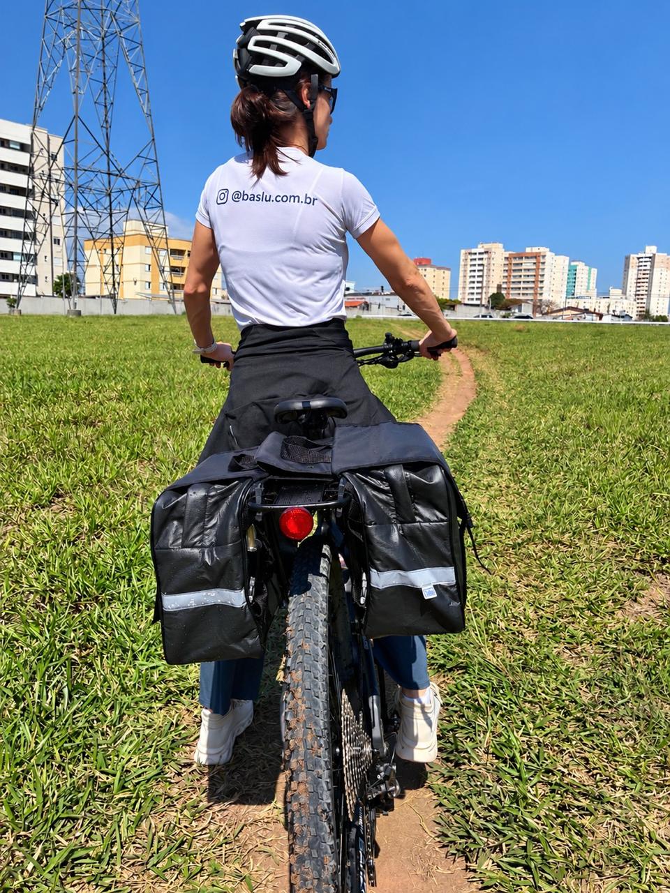 Ciclista com capacete ao lado da bicicleta equipada com o Alforje 40L Bike Baslu preto, em um parque