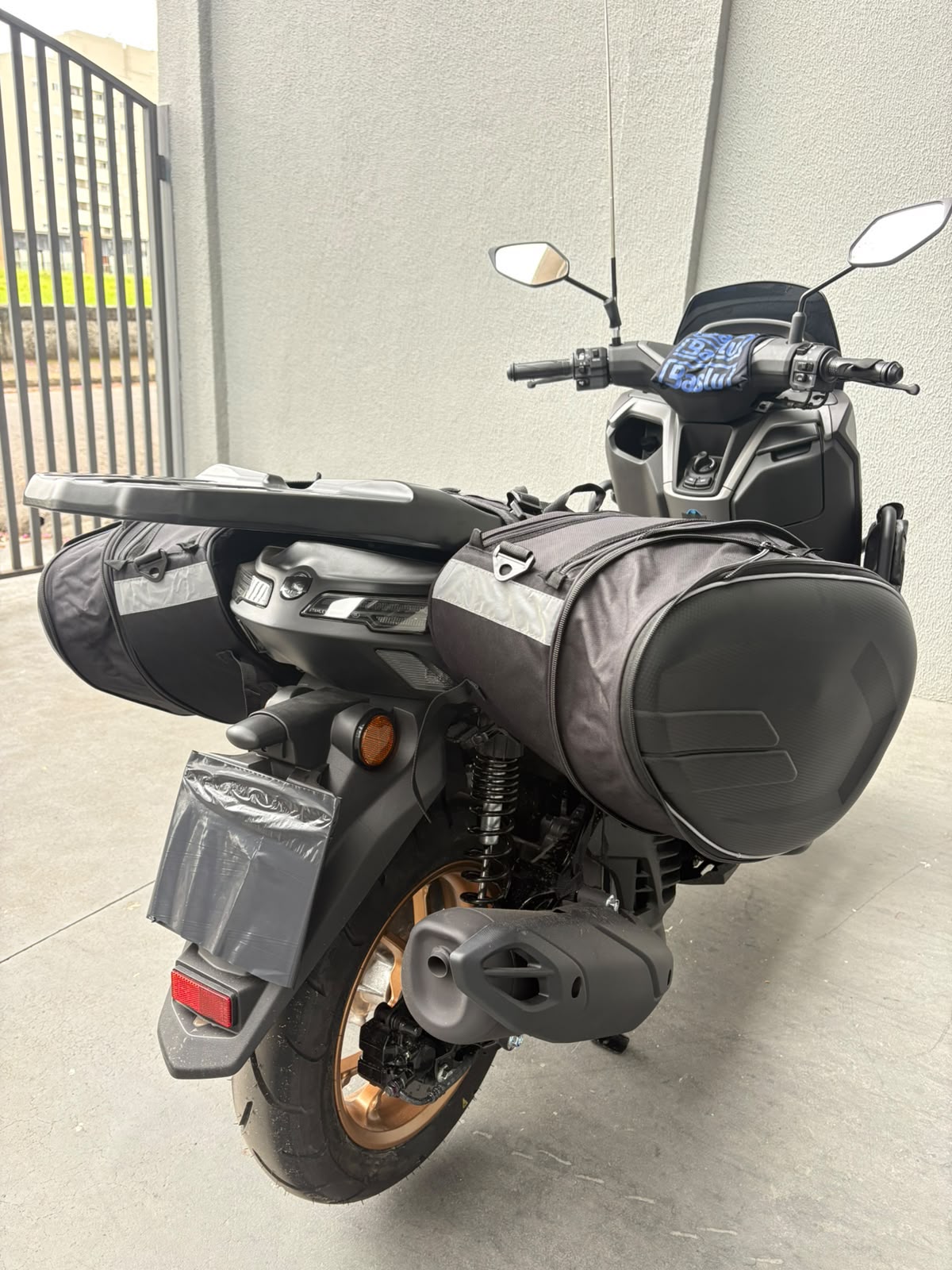 Alforje Baslu 58 litros instalado em moto estacionada, vista traseira lateral